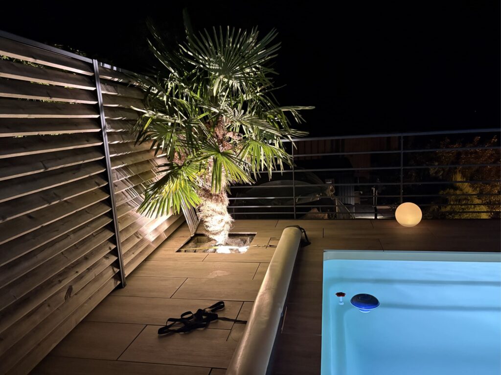 Terrasse et piscine mises en valeur par un éclairage extérieur nocturne