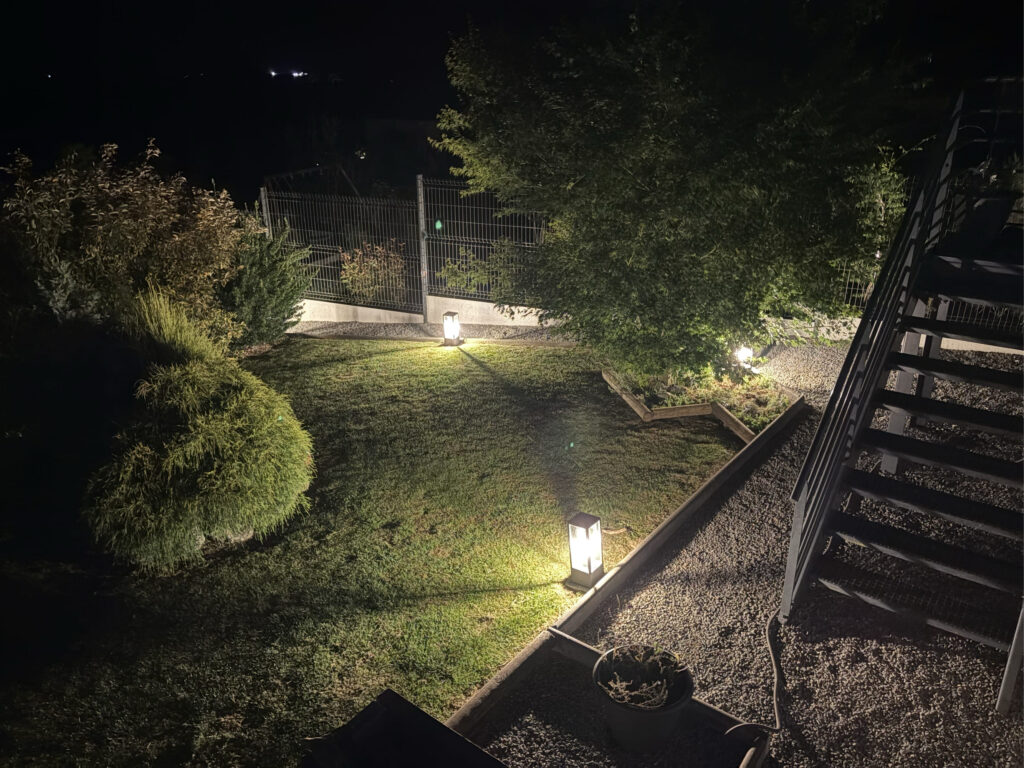 Bornes lumineuses éclairant un jardin et un escalier extérieur la nuit